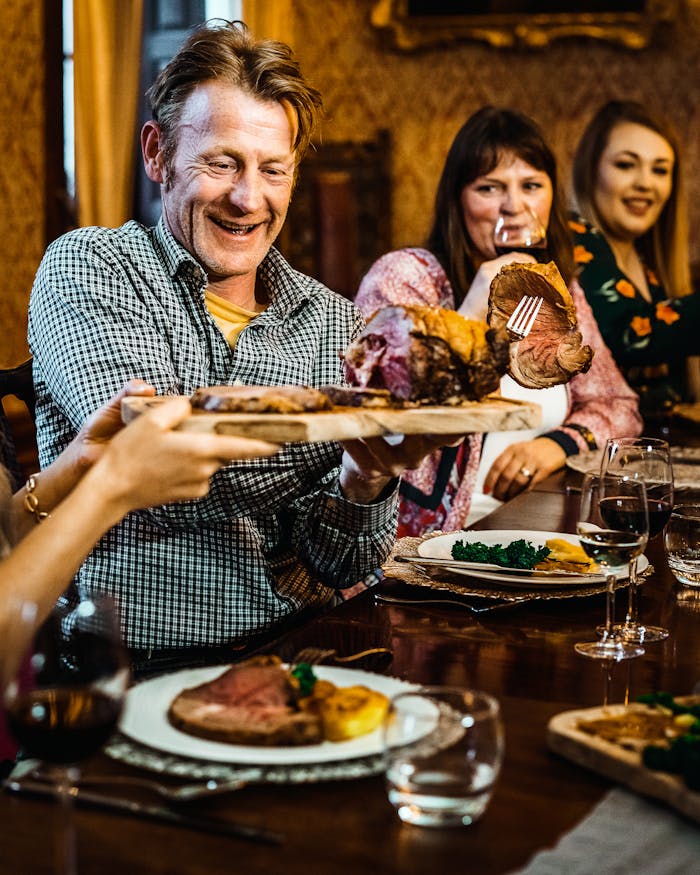Happy group of adults enjoying a hearty meal at a cozy indoor setting.